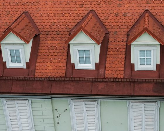 A charming European building with a distinctive red tiled roof and shuttered windows.